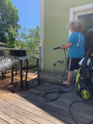 Harvey powerwashing a chair on the back porch