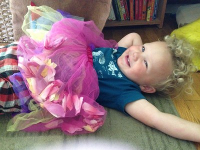 Lijah lying down wearing a pink and purple tutu over his clothes