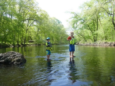Zion and Harvey standing on rocks in the middle of the Assabet River
