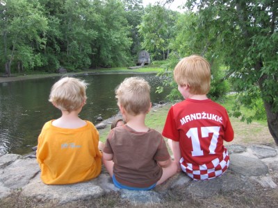 Zion, Lijah, and Nathan sitting on a stone wall above the river