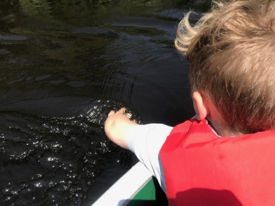 Lijah in the canoe trailing his hand in the water