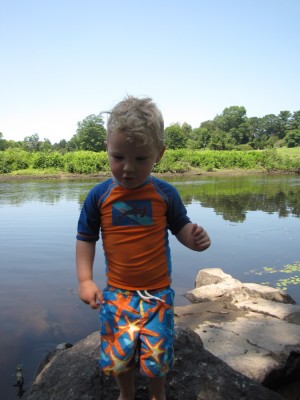 Lijah in his swimsuit on the river bank