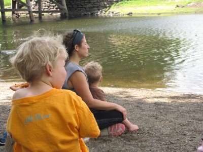 Zion, Mama, and Lijah sitting beside the Concord River