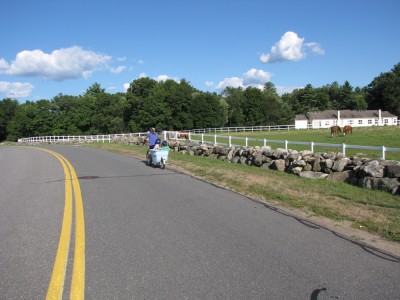 the big bike passing by a sprawling horse farm, with white barns and fences