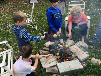 kids roasting pears on sticks over a fire