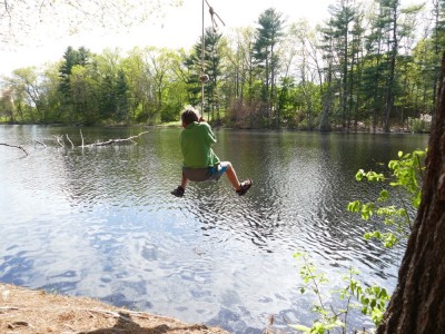 Elijah swining on a rope swing over a pond