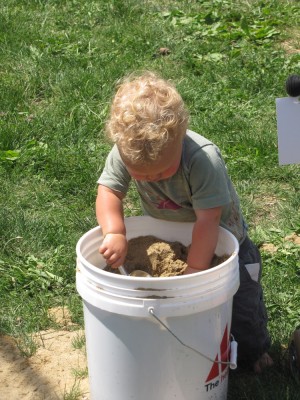 Lijah digging in a five-gallon bucket of sand
