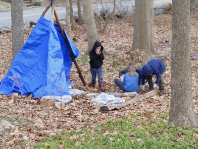 the kids working on a fire by a tarp shelter
