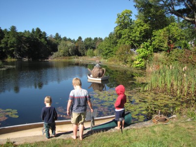 the boys looking at a teapot sculpture alfoat on a pond
