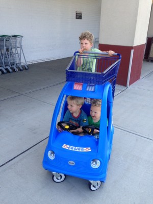 Harvey pushing his brothers in a shopping cart car