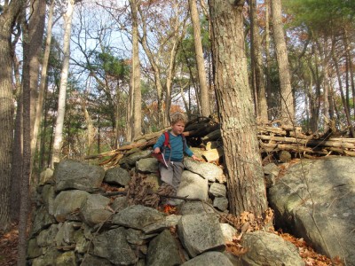 Harvey atop a pile of rocks in the woods, with backpack and sketchbook