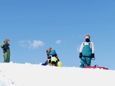 the boys standing against the horizon on the sledding hill