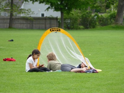 Harvey and Zion lying down with a friend in a soccer goal