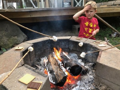 Lijah grimacing at the smoke while toasting a marshmallow
