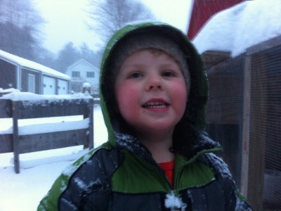 Harvey, snowsuited hooded, smiles for the phone camera next to the chicken coop