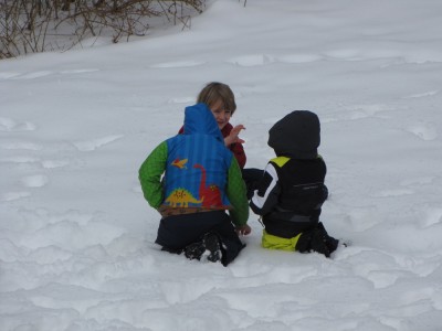 Harvey, Zion, and Eliot kneeling in the snow, deep in coversation