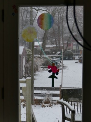 snow falling outside out flower-decorated window