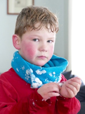 red-cheeked Elijah clearing snow from his shirt cuffs in the living room