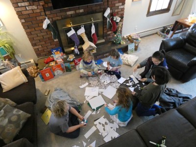 kids sitting in a circle on a friend's floor cutting out paper snowflakes