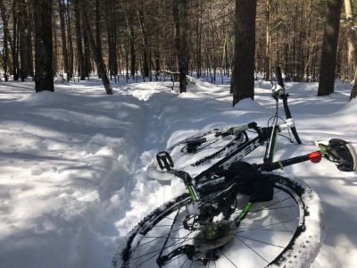 my bike lying in the snow besides a narrow snowy singletrack