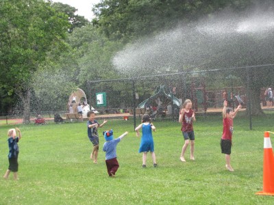 the kids playing in the spray from the firehose