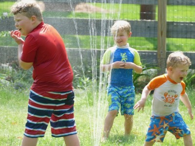 the boys playing in the sprinkler