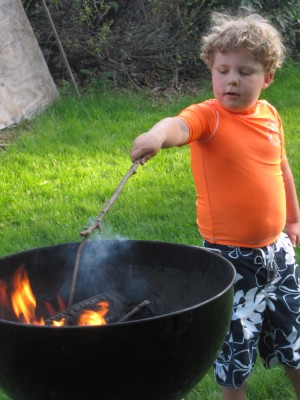 Harvey poking a stick into the fire in the kettle grill