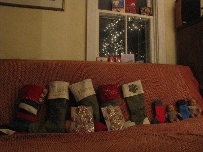 our stockings arrayed on the couch, with gingerbread men for the boys and the tree lights' reflection in the windo