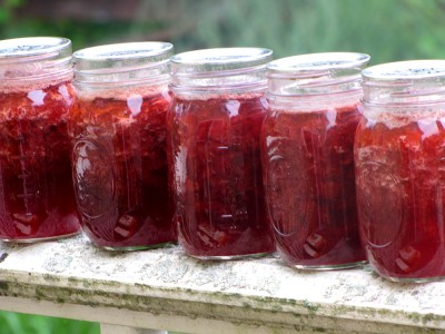 pint jars of strawberry jam on the porch railing