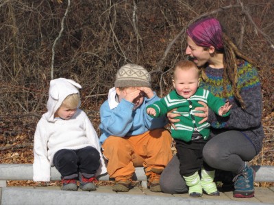Leah and the three boys sitting on a bridge rail, all in home-made sweaters
