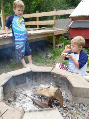 Zion and Lijah in swimsuits by the fire, Zion enjoying a smore