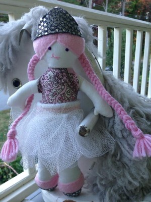 the doll--pink hair, silver crown, dancy skirt--posing on the porch