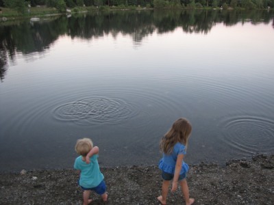 Zion and Taya by the shore of the pond throwing stones