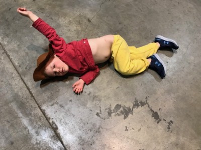 Lijah in a cowboy hat lying on a concrete floor