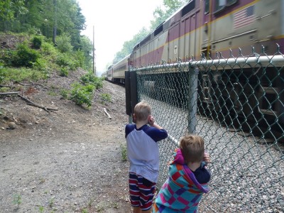 Zion and Lijah holding their ears as a train roars by ten feet away