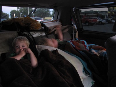 the boys tucked in in the back of the car, at a rest stop