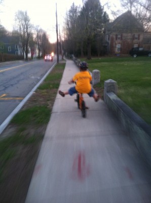 Harvey riding down the twilight street, feet off the pedals