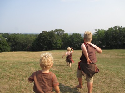 the boys running in a field wearing their historical Wampanoag costumes