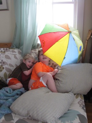 the boys in their swimsuits on the couch with an open umbrella