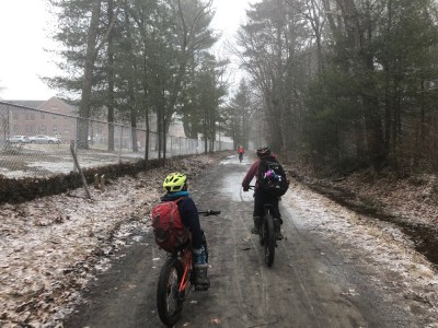 Zion and Elijah riding on a muddy bike path in the falling snow