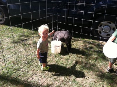 Lijah in the baby goat pen, pointing at one