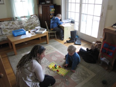 Harvey working at his desk, Zion and Mama playing a board game