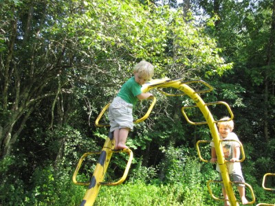 Zion and Harvey playing on a yellow metal climbing structure