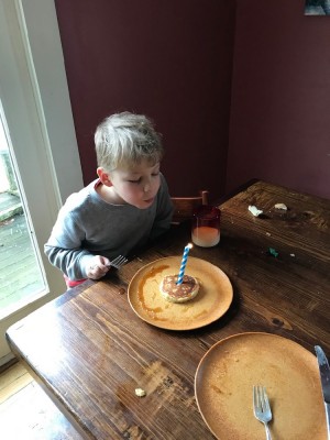 Zion blowing out a candle stuck in a pancake