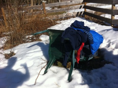 a pile of coats and sweatshirts on a snowy lawn chair