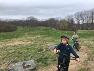 Zion and Elijah on their bikes on a rolling grassy hill
