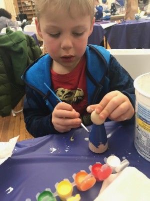 Zion painting a wooden figure at a church event
