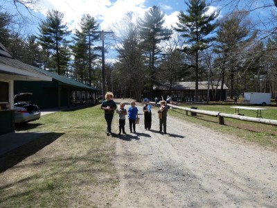 the boys walking on a dirt road on the fair ground, holding bags, balloons, and stuffed animals