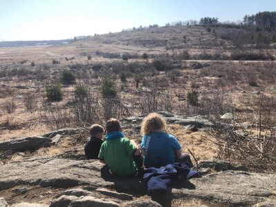 the boys sitting looking down from a scrubby hill