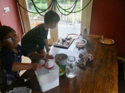 Elijah and a friend mixing muffin batter at the kitchen table
